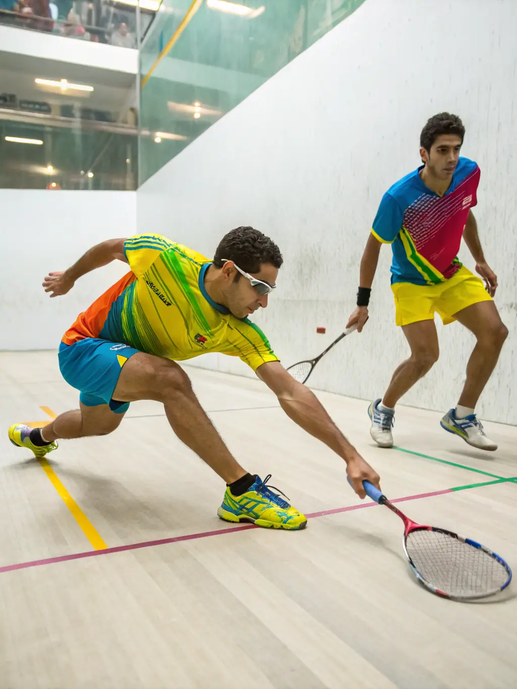 A dynamic shot of adults engaged in a squash match at LAGORD TENNIS SQUASH, showcasing the intensity and fitness aspects of the sport.